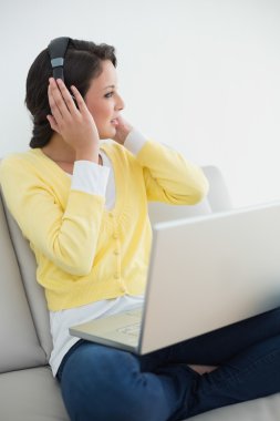 bir dizüstü bilgisayar kullanırken müzik sarı hırka düşünceli casual esmer