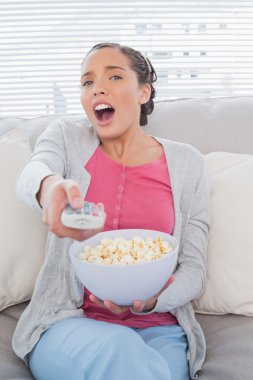 şaşırmış gibi çekici bir kadın tv izlerken patlamış mısır yemek