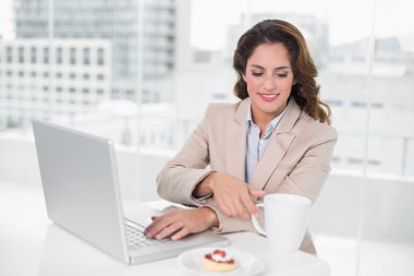 dizüstü bilgisayar masasında kullanarak ve bir kahve olan neşeli bir işkadını