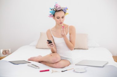 akıllı telefon kullanırken parlatıcısı uygulayarak saç curlers içinde konsantre kadın