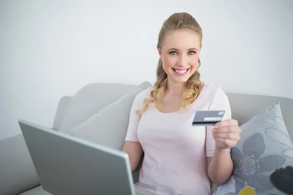 Rubia alegre casual que sostiene el ordenador portátil y la tarjeta de crédito — Foto de Stock