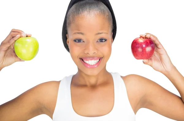 Fit smiling woman holding red and green apple while looking at camera — Stock Photo, Image