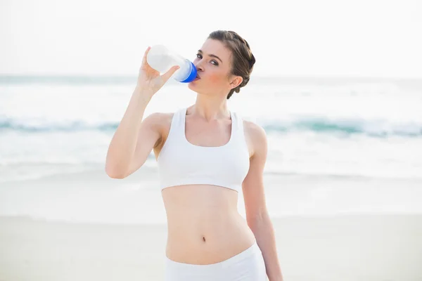 Serious slim model in white sportswear drinking water — Stock Photo, Image