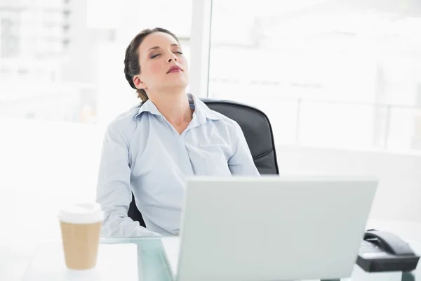 Schläfrig stilvolle brünette Geschäftsfrau entspannt sich an ihrem Schreibtisch — Stockfoto