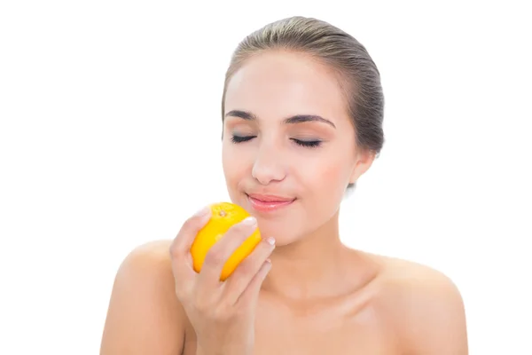 Smiling woman smelling on an orange — Stock Photo, Image