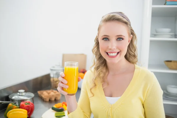 Sorrindo bonito loira segurando um copo de suco de laranja — Fotografia de Stock