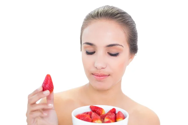 Content woman holding up a strawberry with closed eyes — Stock Photo, Image
