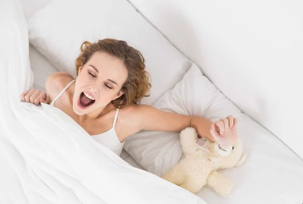 Yawning brunette sitting next to teddy bear — Stock Photo, Image