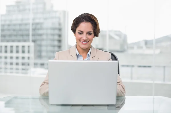 Mujer de negocios sonriente usando portátil en su escritorio — Foto de Stock