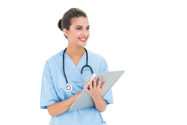 Enfermeira atraente em esfoliação azul verificando um relatório — Fotografia de Stock
