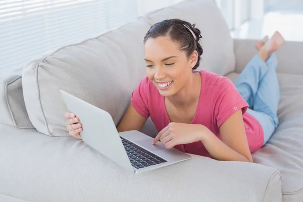 Счастливая женщина с ноутбуком на диване — стоковое фото