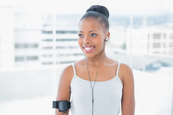 Smiling attractive woman in sportswear listening to music — Stock Photo, Image