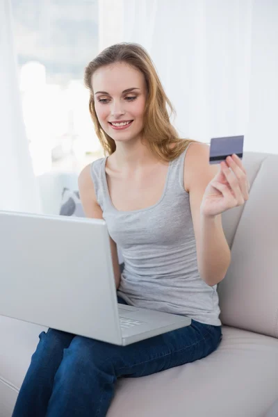 漂亮的女人坐在沙发上使用便携式计算机在线购物 — 图库照片