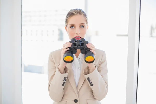 Astonished blonde businesswoman holding binoculars — Stock Photo, Image