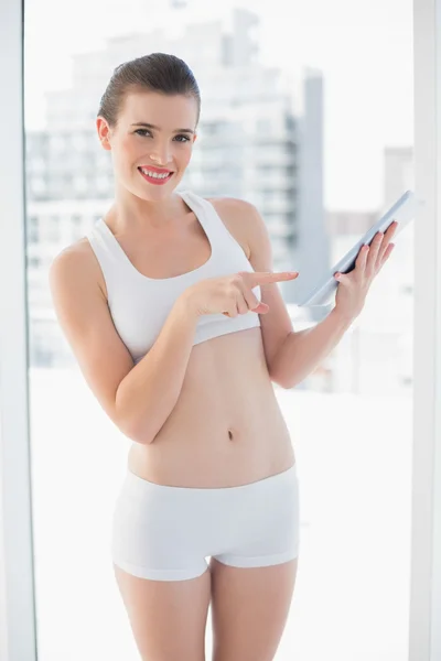 Pleased fit model in sportswear using a tablet pc — Stock Photo, Image