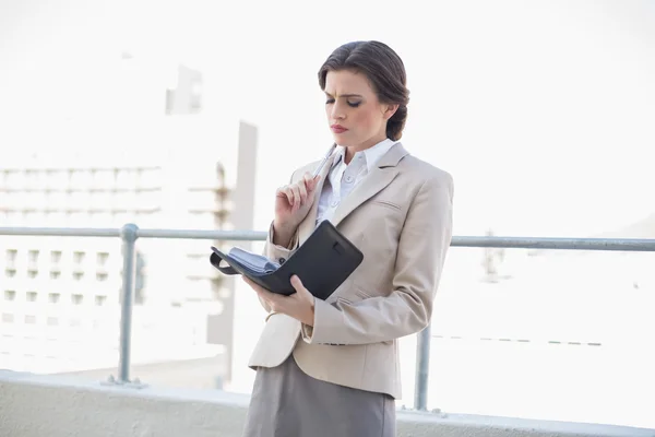 Fruncir el ceño elegante mujer de negocios llenando su horario —  Fotos de Stock