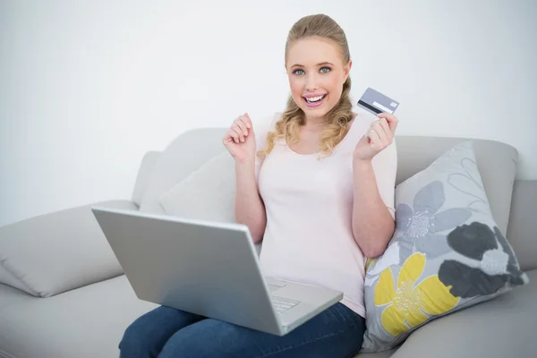 Casual loira emocionada segurando cartão de crédito e laptop — Fotografia de Stock