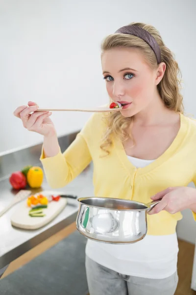 Cute blonde tasting food from wooden spoon — Stock Photo, Image