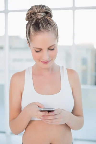 Happy sporty blonde text messaging — Stock Photo, Image
