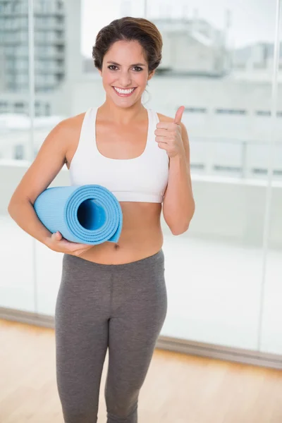 Sportieve lachende brunette bedrijf uitoefening mat — Stockfoto