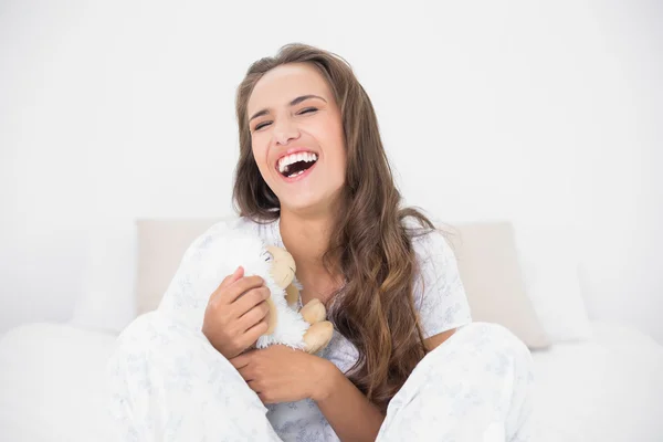 Laughing attractive brunette holding a soft toy — Stock Photo, Image