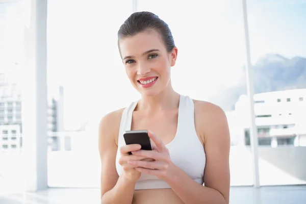 Modello piuttosto in forma in abbigliamento sportivo utilizzando il suo telefono cellulare — Foto Stock