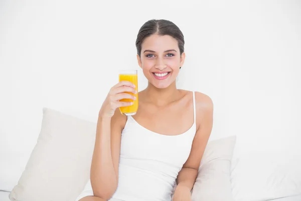 Modelo em pijama branco segurando um copo de suco de laranja — Fotografia de Stock