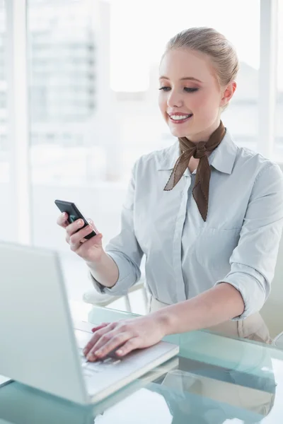 Bionda sorridente donna d'affari utilizzando laptop e smartphone — Foto Stock