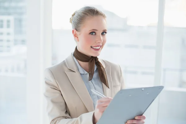 Blonde smiling businesswoman holding clipboard — Stock Photo, Image