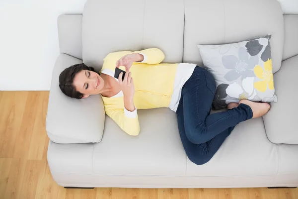 Morena casual relajada en cárdigan amarillo usando un teléfono móvil — Foto de Stock