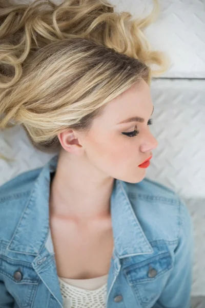 Pensive blonde wearing denim clothes lying on stairs — Stock Photo, Image