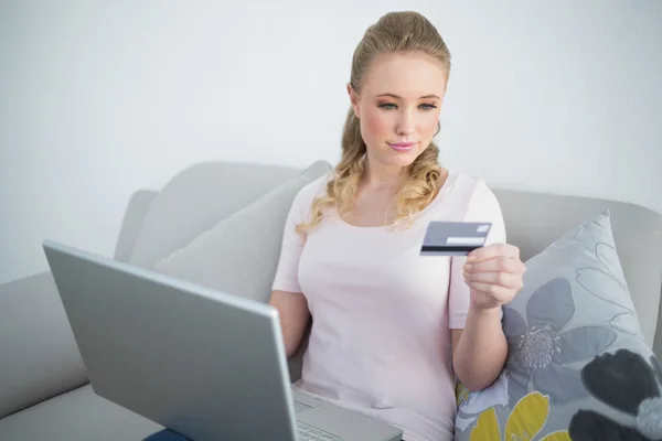 Свободный контент блондинка с ноутбуком и глядя на кредитную карту — стоковое фото