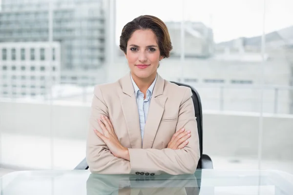 Gelukkig zakenvrouw op haar bureau met gekruiste armen — Stockfoto