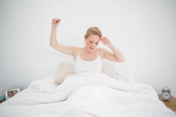 Natürliche gähnende Blondine sitzt mit geschlossenen Augen im Bett — Stockfoto