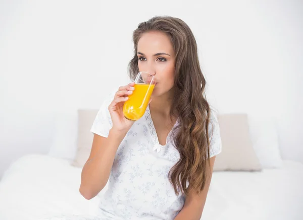 オレンジ ジュースのガラスを飲む穏やかなブルネット — ストック写真