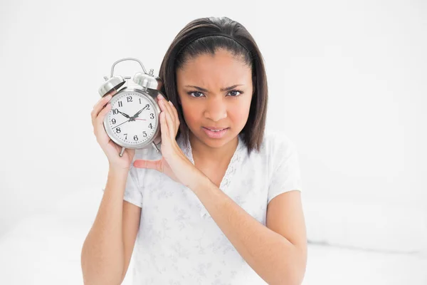 Frowning young model holding an alarm clock — Stock Photo, Image