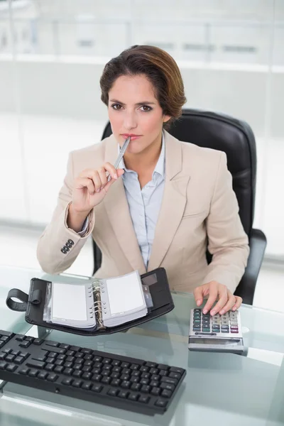 Nachdenkliche Geschäftsfrau mit Taschenrechner — Stockfoto