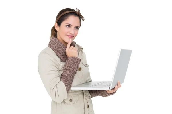 Στοχαστικό χαριτωμένο brunette στην χειμερινή μόδα χρησιμοποιώντας φορητό υπολογιστή — Φωτογραφία Αρχείου