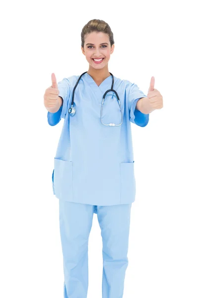 Joyful nurse in blue scrubs giving thumbs up — Stock Photo, Image