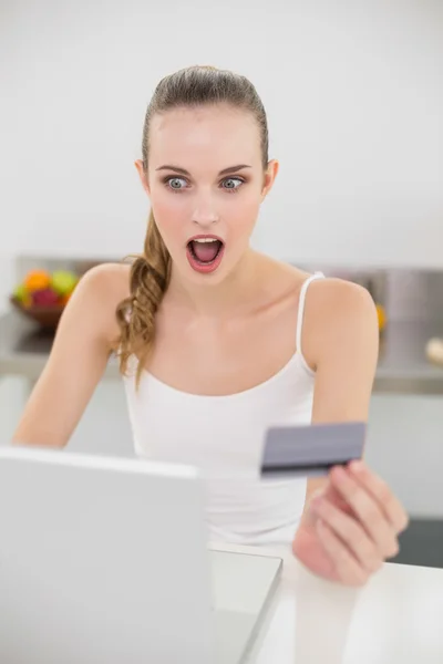 Geschokt jonge vrouw met behulp van haar laptop voor online winkelen — Stockfoto