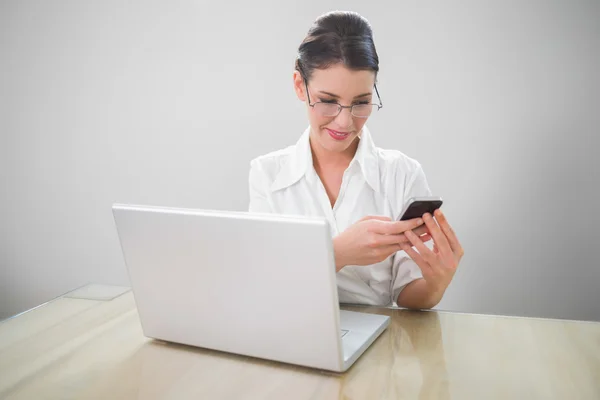 Glimlachende zakenvrouw met stijlvolle glazen texting — Stockfoto