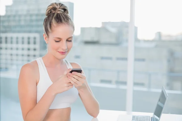 Lächelnde sportliche Blondine schickt einen Text — Stockfoto