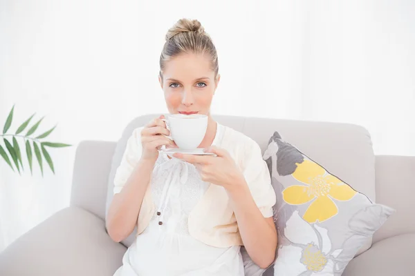 Charming fresh model drinking coffee sitting on sofa — Stock Photo, Image