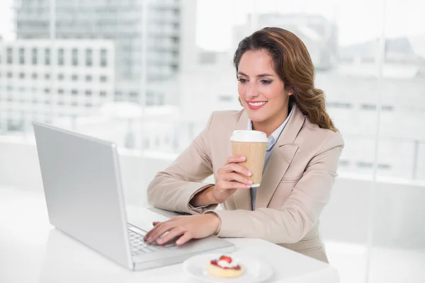 O femeie de afaceri care bea cafea la birou folosind laptopul — Fotografie, imagine de stoc