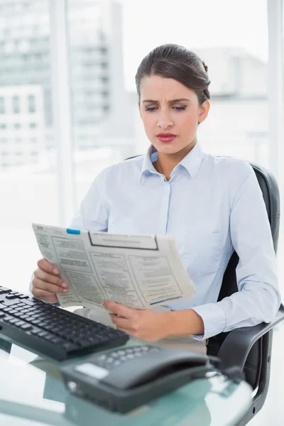 Empresaria frunciendo el ceño leyendo un periódico — Foto de Stock