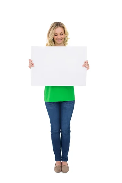 Smiling cute blonde holding white poster — Stock Photo, Image