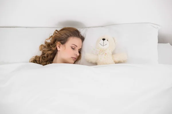 Atractiva morena durmiendo junto al osito de peluche — Foto de Stock