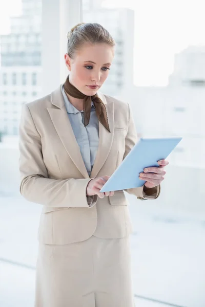 Blonde serious businesswoman looking at tablet — Stock Photo, Image
