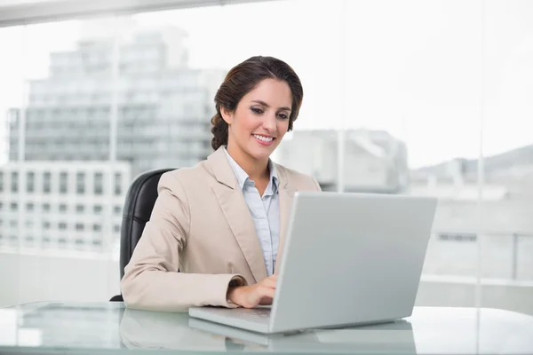 Heureuse femme d'affaires tapant sur ordinateur portable à son bureau — Photo