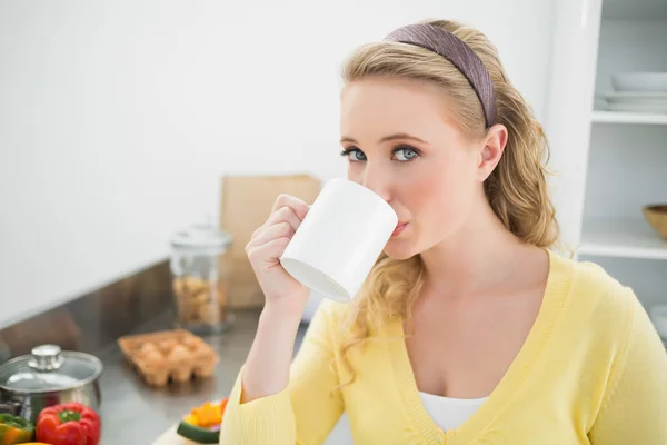 Innehåll söt blondin dricka ur en mugg — Stockfoto